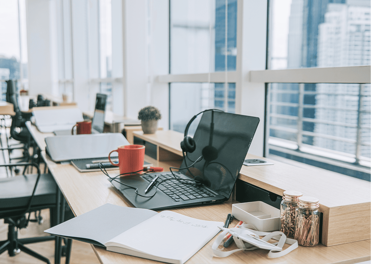 Modern office workspace with laptops and notebooks.